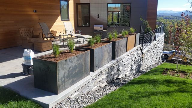 Large metal planter lining a back patio containing decorative grass